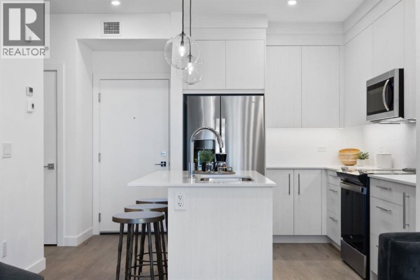 View of a modern kitchen with white cabinets, stainless steel refrigerator, and island. - 2210, 44 Skyview Parkway Ne, Calgary