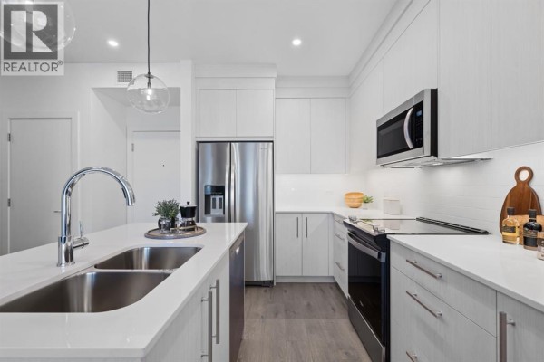 Modern kitchen featuring white cabinets, a stainless steel refrigerator, and quartz countertops. - 2210, 44 Skyview Parkway Ne, Calgary