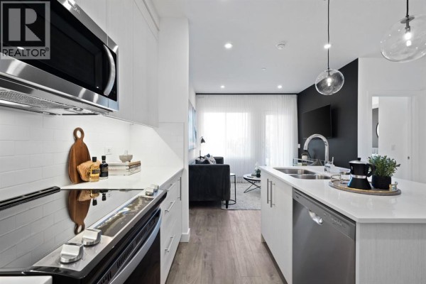 View of an open-concept living space with a modern kitchen, island, and living room. - 2210, 44 Skyview Parkway Ne, Calgary
