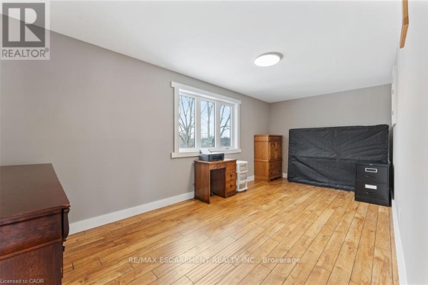 Wooden desk, printer, cabinet, mattress, and filing cabinet in a room with hardwood floors - 2210 Highway 54 Haldimand