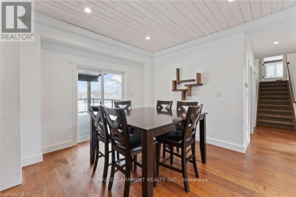 Dining room with dark wood table and chairs, deck access, and hardwood floors - 2210 Highway 54 Haldimand