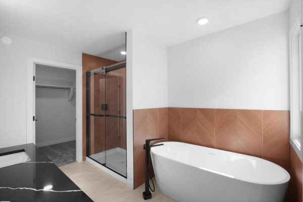 Spacious bathroom featuring a large vanity with black countertop, tub, and separate walk-in closet. - 22108 94 Av Nw, Edmonton