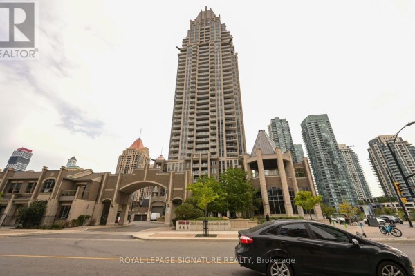 Exterior of a tall, modern apartment building with an arched entrance and surrounding cityscape. - 2211 - 388 Prince Of Wales Drive, Mississauga
