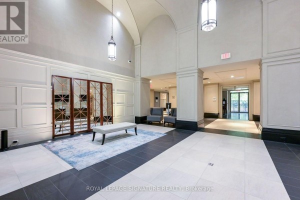 Building lobby with vaulted ceiling, tiled floor, bench, decorative screen, and seating area. - 2211 - 388 Prince Of Wales Drive, Mississauga