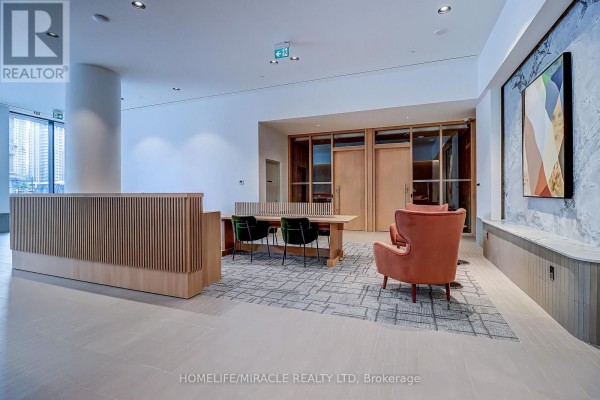 Building lobby with a slatted wood reception desk, seating area, and abstract art. - 2211 - 395 Square One Drive, Mississauga