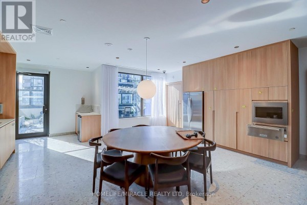 Round dining table with chairs in a bright room with light wood cabinetry and stainless steel appliances. - 2211 - 395 Square One Drive, Mississauga