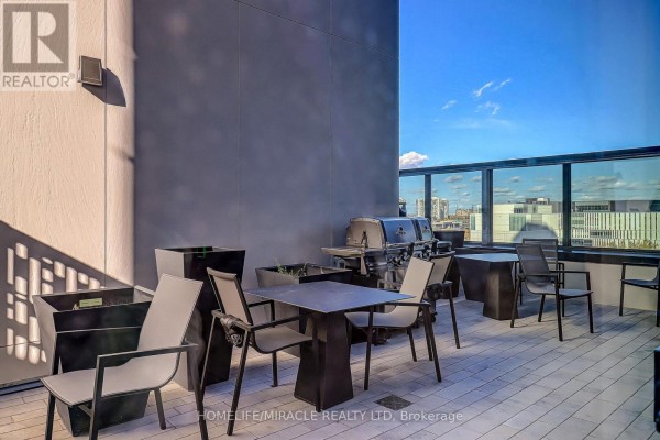 Outdoor terrace with patio furniture, grills, and city views through a glass railing. - 2211 - 395 Square One Drive, Mississauga