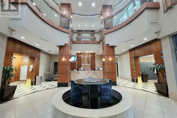 Building lobby with a water feature, reception desk, wood paneling, and mailboxes. - 2213 - 10 Northtown Way, Toronto