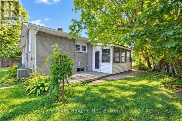 Rear exterior view showing a wooden deck, sunroom addition, and backyard. - 2213 Circle Place, Ottawa