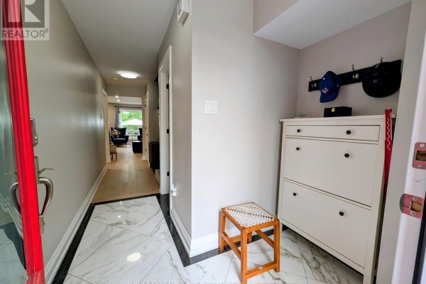 Entryway with light grey walls, white shoe cabinet, orange stool, and marble tile flooring. - 2213 Ridge Landing, Oakville
