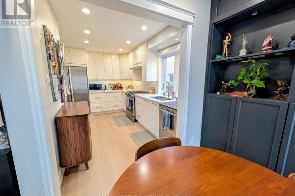 U-shaped kitchen with cream cabinets, stainless steel appliances, and a small dining area. - 2213 Ridge Landing, Oakville