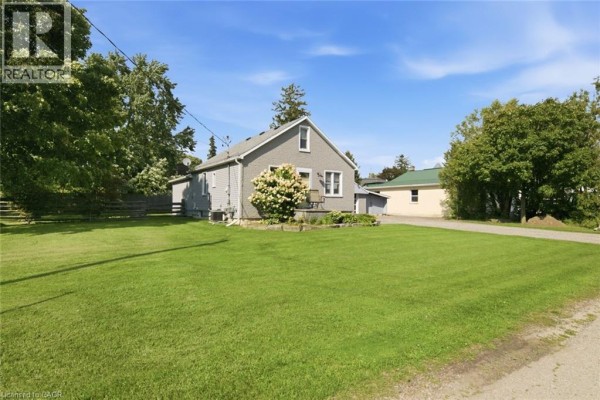 Side exterior view of the grey house, garage, and expansive green lawn. - 2214 William Shakespeare Street, Shakespeare