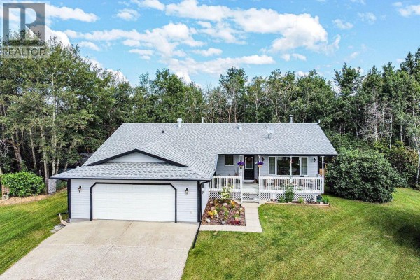 Front view of a bungalow with an attached garage, white siding, and a manicured lawn. - 22148 Twp Rd 464a, Rural Camrose County