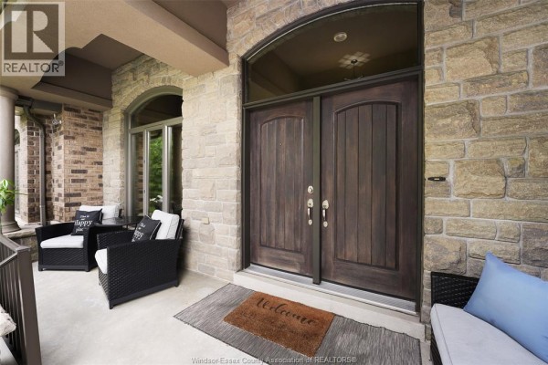 Covered front porch with wicker chairs and a double wooden front door. - 2216 Roxborough, Windsor