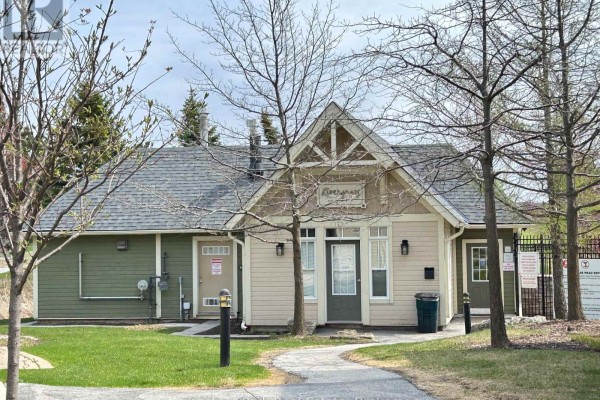 Small building with beige and green siding, pitched roof, and pathways. - 222 - 125 Fairway Court, Blue Mountains