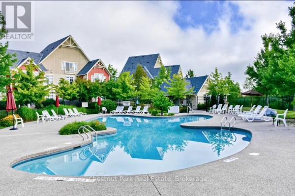 Resort-style swimming pool with lounge chairs and surrounding townhouses. - 222 - 125 Fairway Court, Blue Mountains
