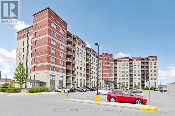View of the apartment building with a parking lot in the foreground. - 222 - 39 New Delhi Drive N, Markham