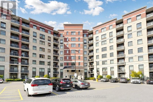 U-shaped apartment building exterior with balconies and parking lot. - 222 - 39 New Delhi Drive N, Markham
