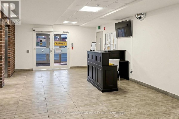 Building lobby with a dark wood reception desk and tiled floor. - 222 - 39 New Delhi Drive N, Markham