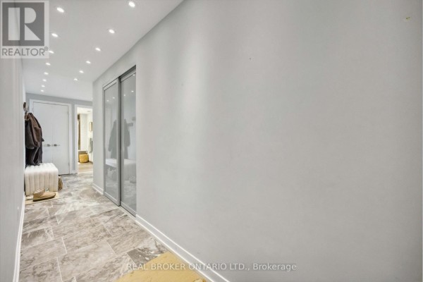 Long hallway with tiled floors, recessed lighting, and mirrored closet doors. - 222 - 95 Bathurst Street, Toronto