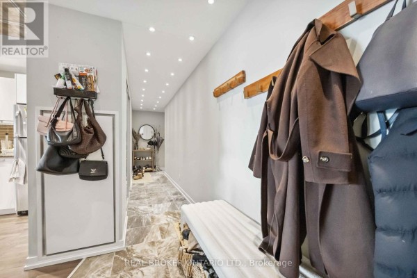 Hallway with a bench, wooden coat hooks, and bags hanging on a wall organizer. - 222 - 95 Bathurst Street, Toronto