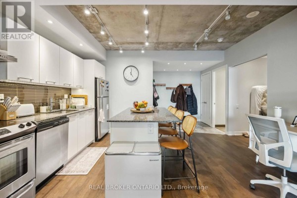 Kitchen with white cabinets, stainless steel appliances, and an island with bar stools. - 222 - 95 Bathurst Street, Toronto