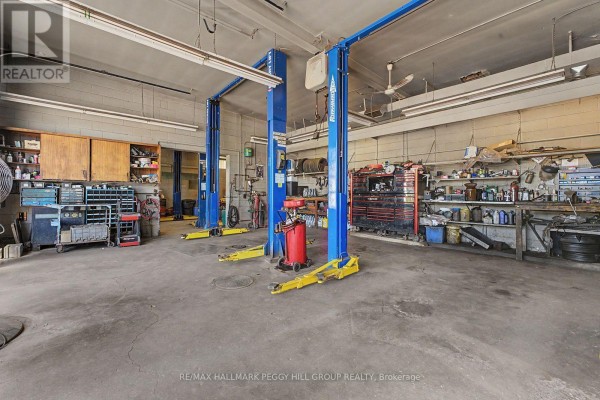 Auto repair garage interior with two blue car lifts, tool chests, shelves, and workbench. - 222 Blake Street, Barrie