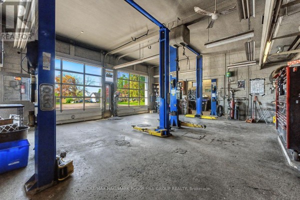 View from inside the garage looking out through open bays with car lifts and tools. - 222 Blake Street, Barrie