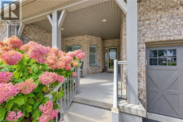 Covered front porch with chairs, pink flowers, and view into the entrance. - 222 Chestnut Hill Crescent, Kitchener