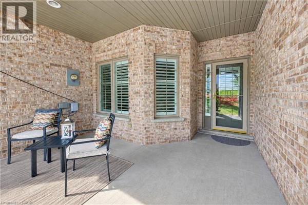 Covered porch with seating and view through glass door to a green lawn. - 222 Chestnut Hill Crescent, Kitchener