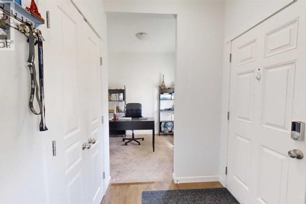 Interior view of the entryway showing a white door, double closet, and office space. - 222 Copperpond Boulevard Se, Calgary