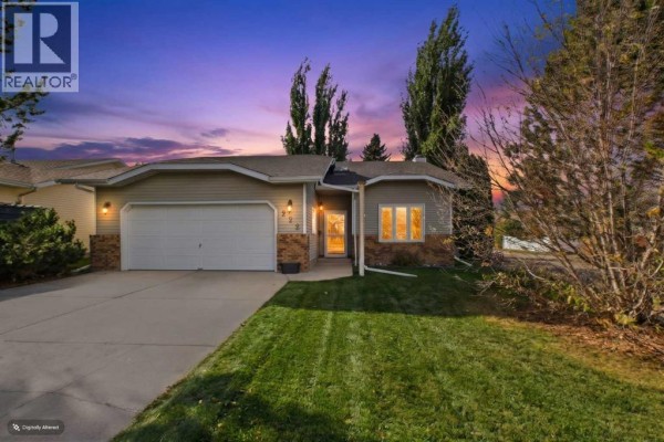 Front exterior of a bungalow with a double garage door at dusk. - 222 Davison Drive, Red Deer