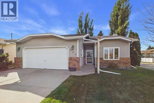 Front exterior of a bungalow with a double garage door and brick accents. - 222 Davison Drive, Red Deer