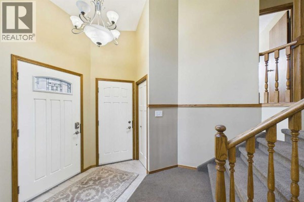 Interior entryway with two white doors, a carpeted staircase, and wood trim details. - 222 Davison Drive, Red Deer