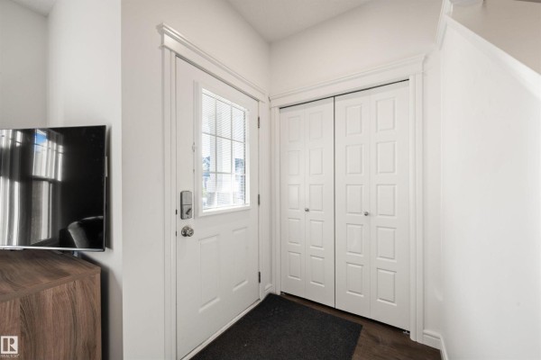 Entranceway with a white door, frosted glass, a smart lock, and a coat closet. - 222 Desrochers Bv Sw, Edmonton