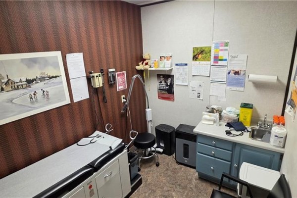 Medical examination room with an exam table, sink, and patient charts. - 222 Fairview Drive Unit# 205, Brantford