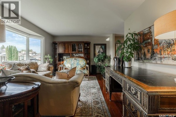 Living room with a bay window, sofa, ornate desk, and built-in cabinet. - 222 Gathercole Crescent, Saskatoon