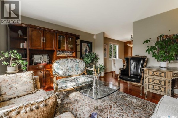 Living room featuring a decorative sofa, black armchair, glass table, and built-in cabinet. - 222 Gathercole Crescent, Saskatoon