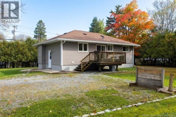 Rear exterior view of the house with a wooden deck and patio doors. - 222 Gondola Point Road, Rothesay