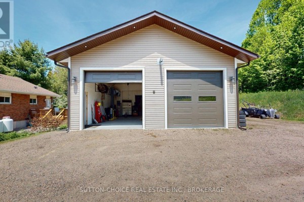 Exterior of a detached two-car garage with beige siding and grey garage doors. - 222 Yonge Street, Bonfield