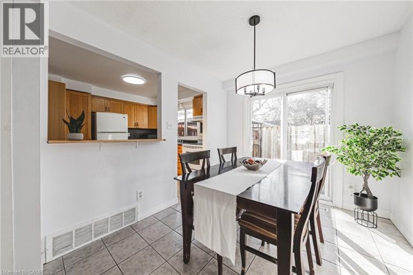 Cozy living area with sectional sofa, large window, and decorative lamp, featuring hardwood floors. - 2220 Upper Middle Road Unit# 4, Burlington