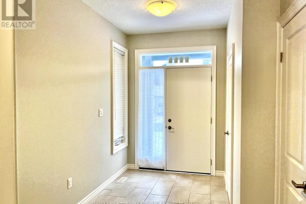Entrance hallway with tiled floor, beige walls, and double front doors with sidelights. - 2225 Tribalwood Street, London North