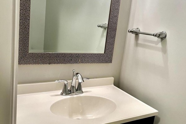 Powder room with a white sink, chrome faucet, and a decorative framed mirror. - 2225 Tribalwood Street, London North