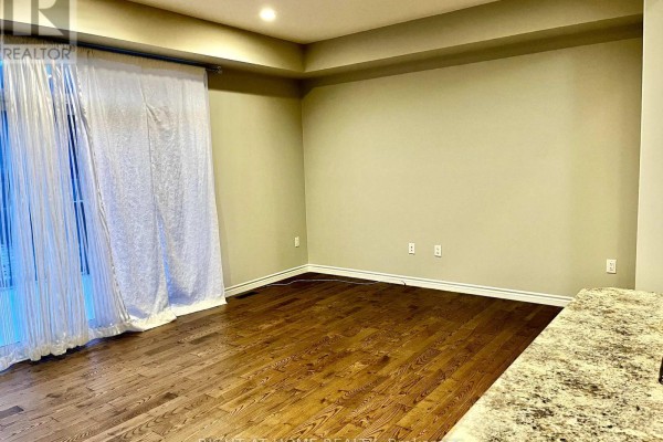Empty dining room with dark hardwood floors, beige walls, and a granite countertop edge. - 2225 Tribalwood Street, London North