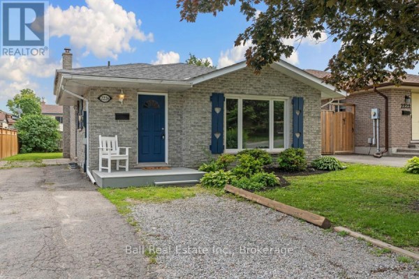 Front exterior view of a bungalow with grey brick, blue shutters, at dusk. - 2226 Springwood Road, Peterborough