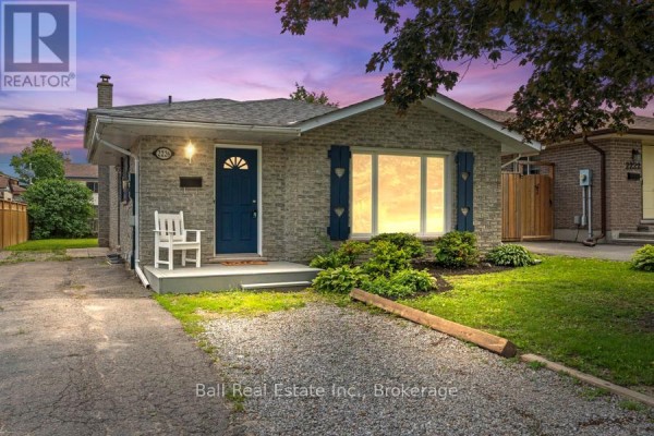 Front exterior view of a bungalow with grey brick and a large maple tree. - 2226 Springwood Road, Peterborough