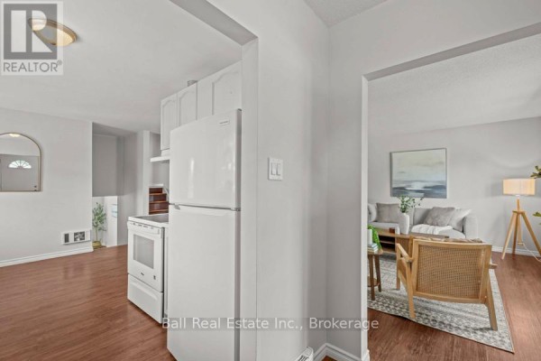 Interior view showing a white refrigerator and kitchen appliances, with living room beyond. - 2226 Springwood Road, Peterborough