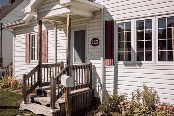 Close-up of the front door, wooden steps, and mailbox of a white house. - 223 Dover Street, Campbellton