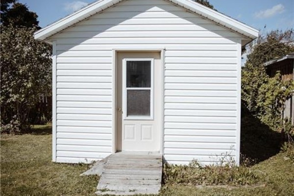 Exterior of a detached white shed with a ramp leading to its door. - 223 Dover Street, Campbellton