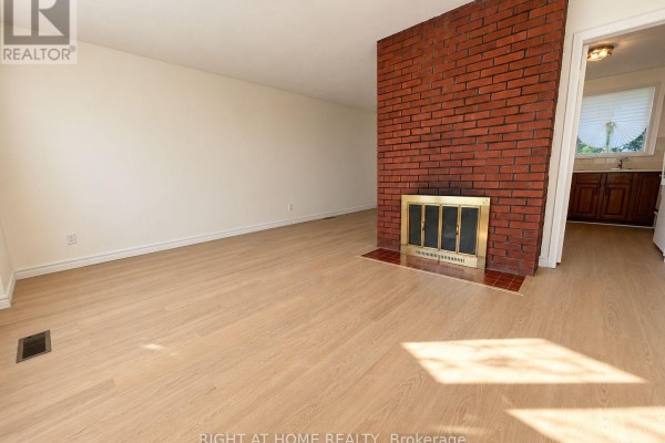 Living room with light wood flooring, white walls, and a large red brick fireplace. - 223 Ellendale Drive, Toronto
